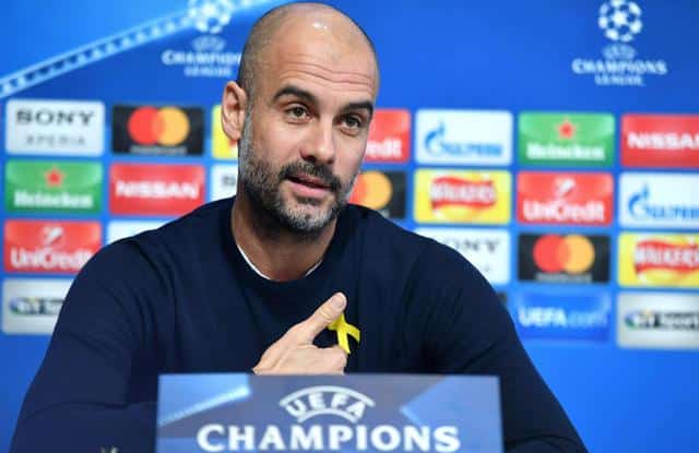 epa06584522 Manchester City manager Pep Guardiola gestures towards a yellow ribbon worn to support those campaigning for Catalan independence during a press conference at the Manchester City training ground in Manchester, Britain, 06 March 2018. Mancheste